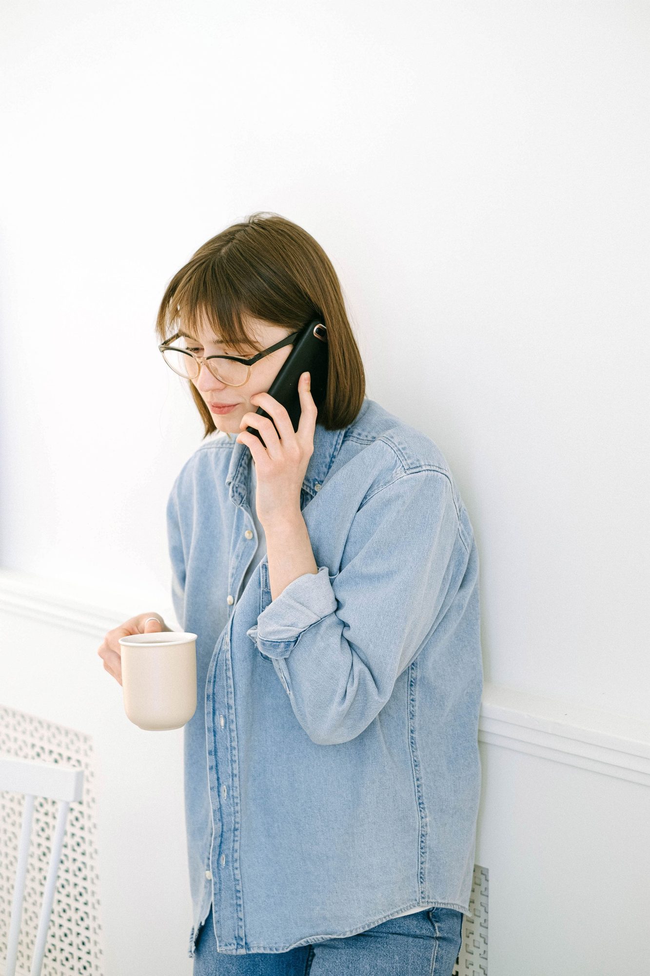 A woman holding a coffee mug while asking a question on her phone