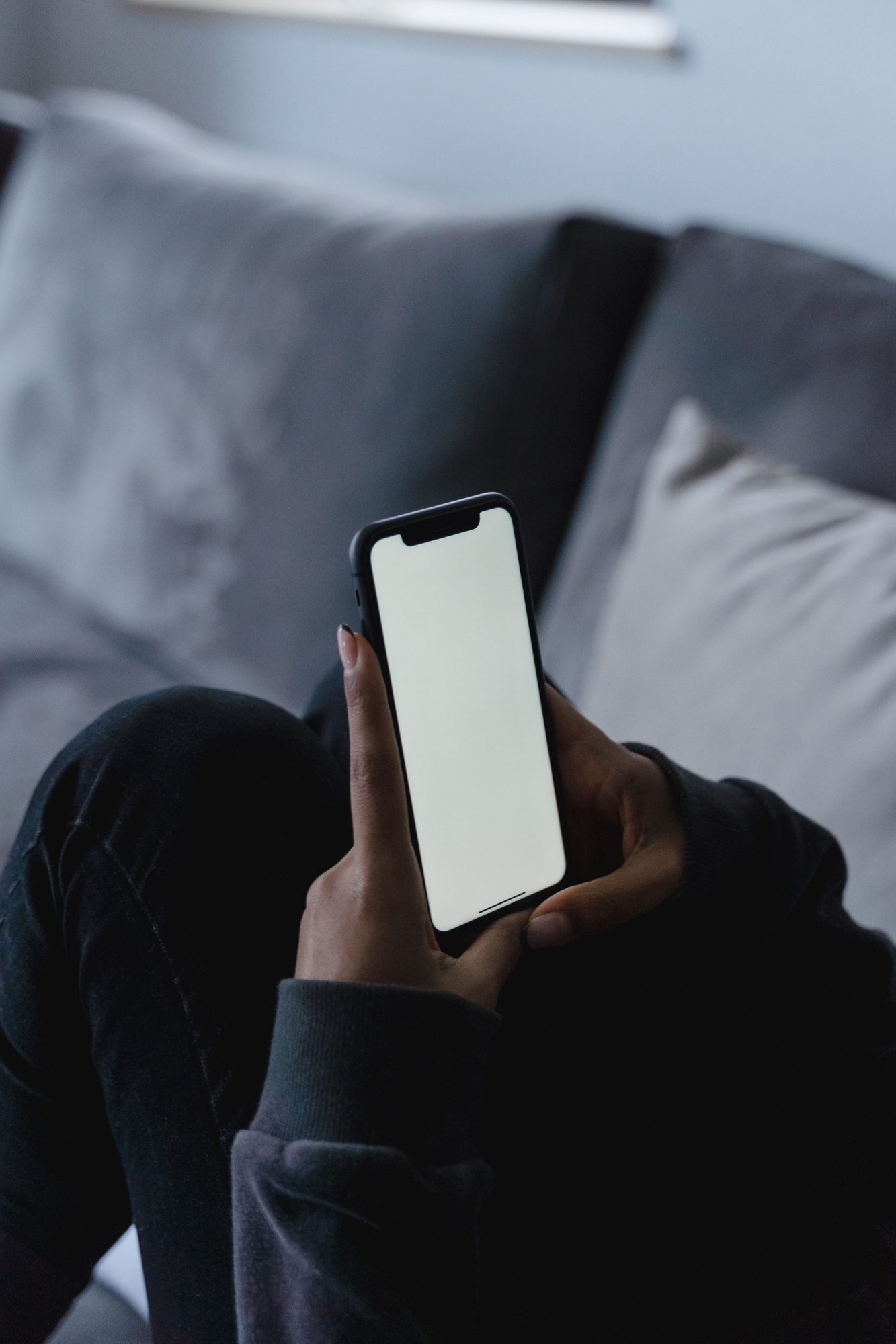 Hands holding a phone on the sofa in the evening, asking Remy about the day