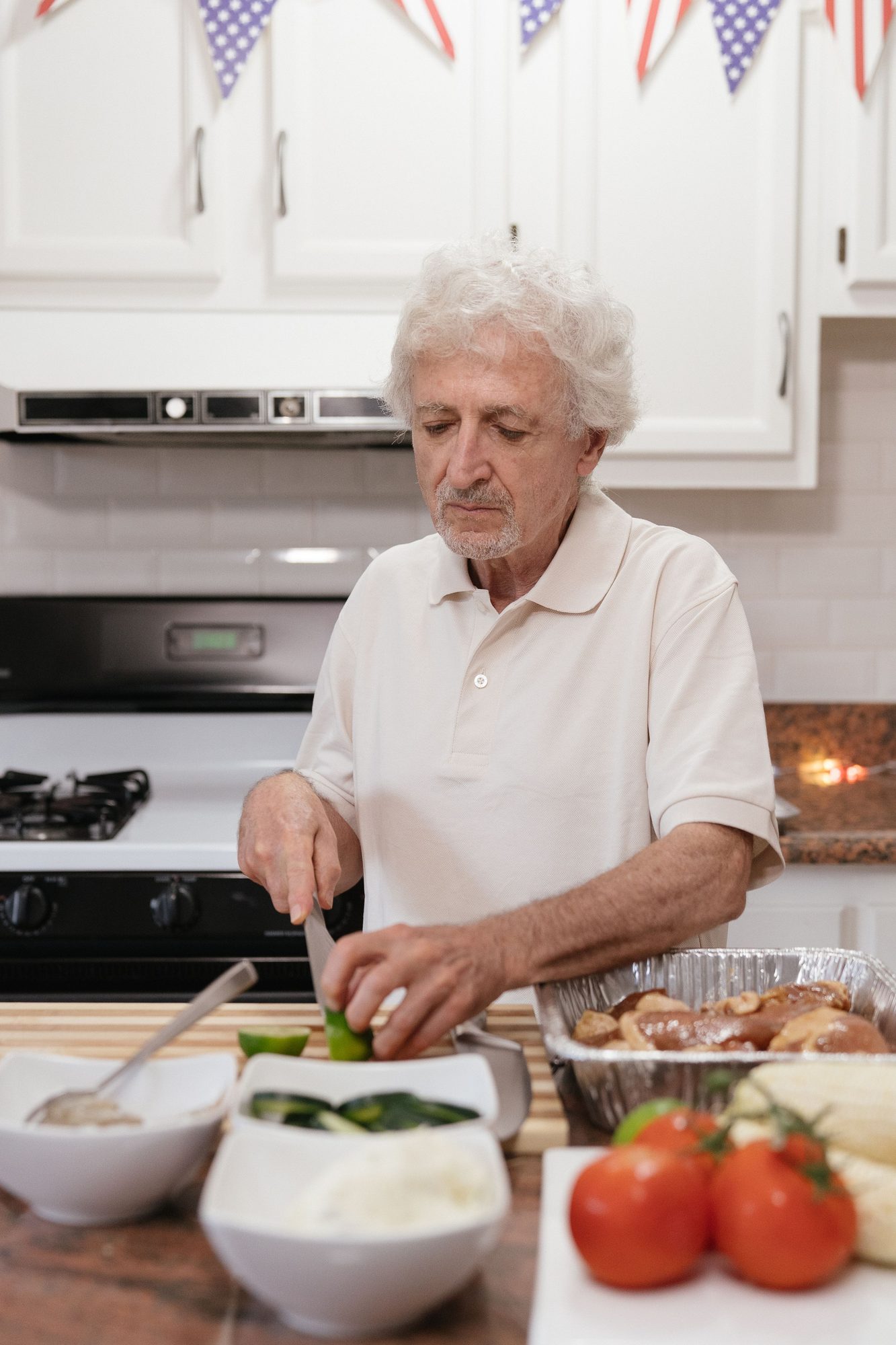 An older man preparing food at his kitchen counter beside the stove