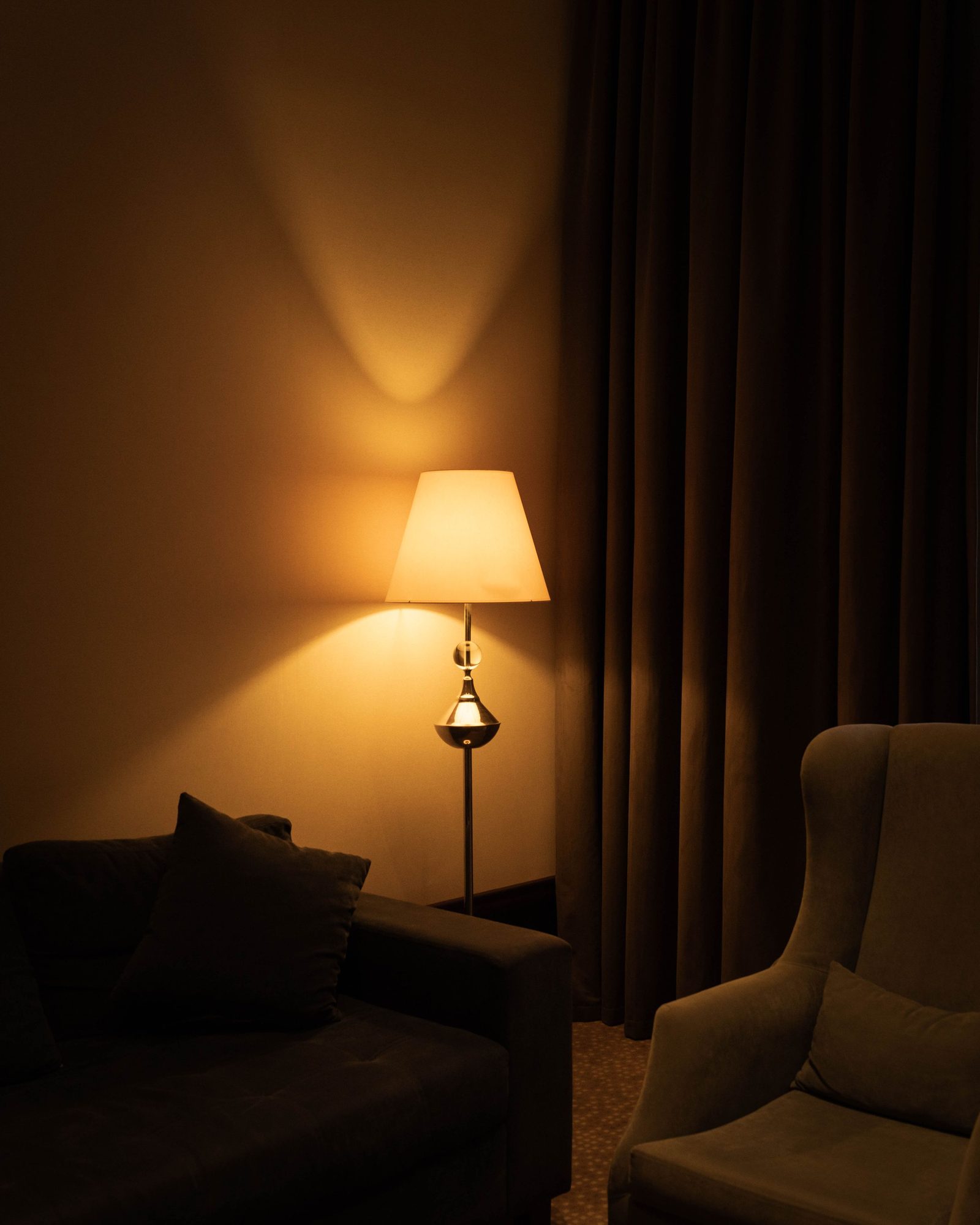 A warm lamp glowing in a dark living room corner at night